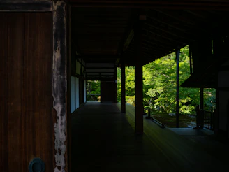 A sunlit veranda of a traditional Kerala homestay surrounded by lush greenery and blooming flowers.