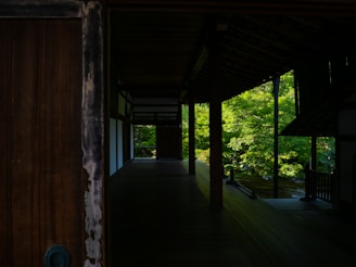 A spacious open-air living room with natural wood accents and views of the garden.