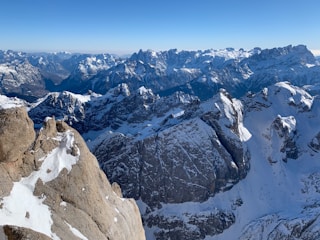 A panoramic view of rugged Himalayan mountains with miners extracting pink salt under clear blue skies.
