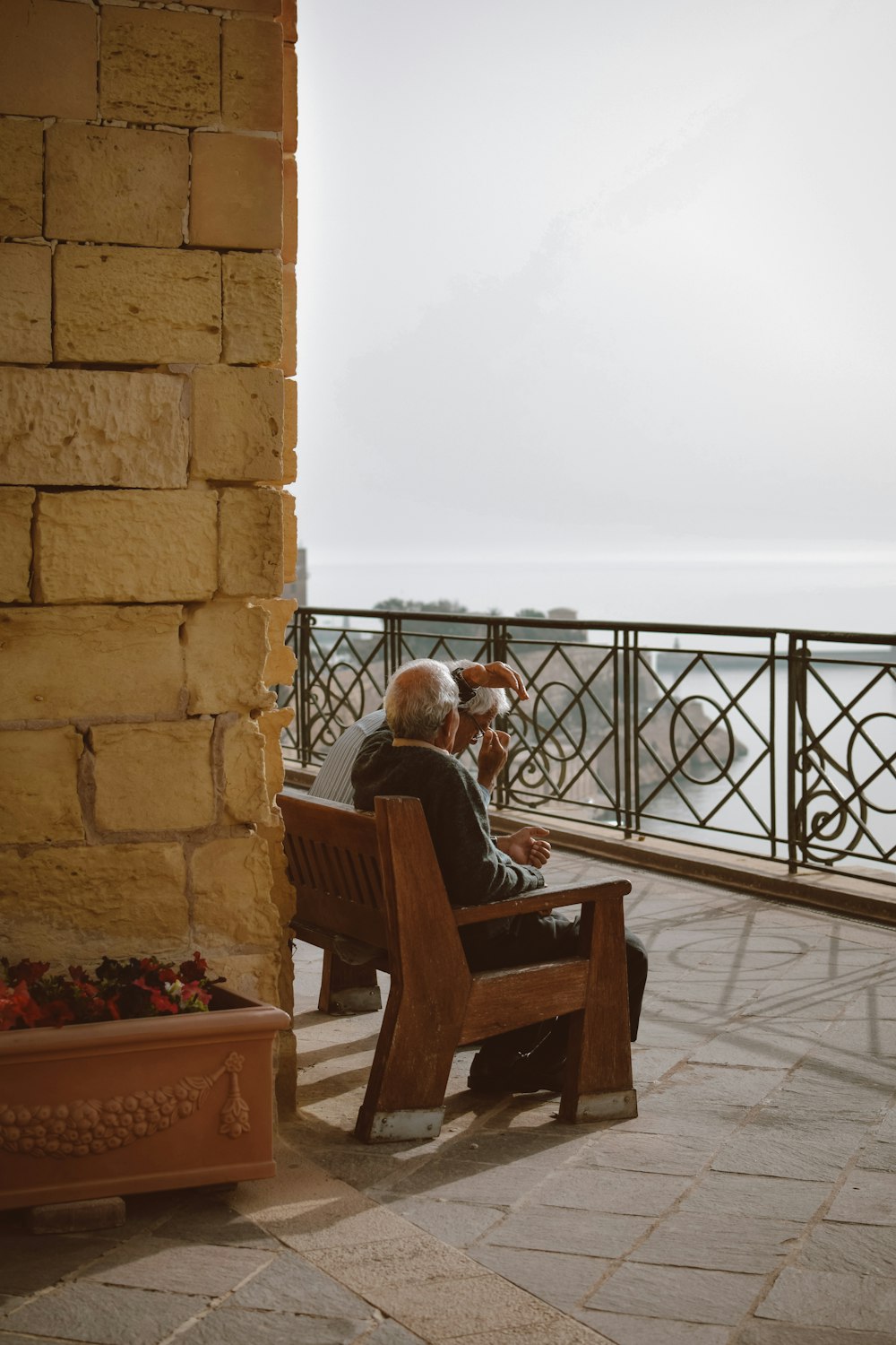 a couple of people sitting on a bench looking out over the water