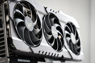 A close-up view of a graphics card with three large cooling fans and metallic accents. The card is housed within a computer case, showcasing intricate hardware design.