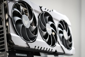 A close-up view of a graphics card with three large cooling fans and metallic accents. The card is housed within a computer case, showcasing intricate hardware design.