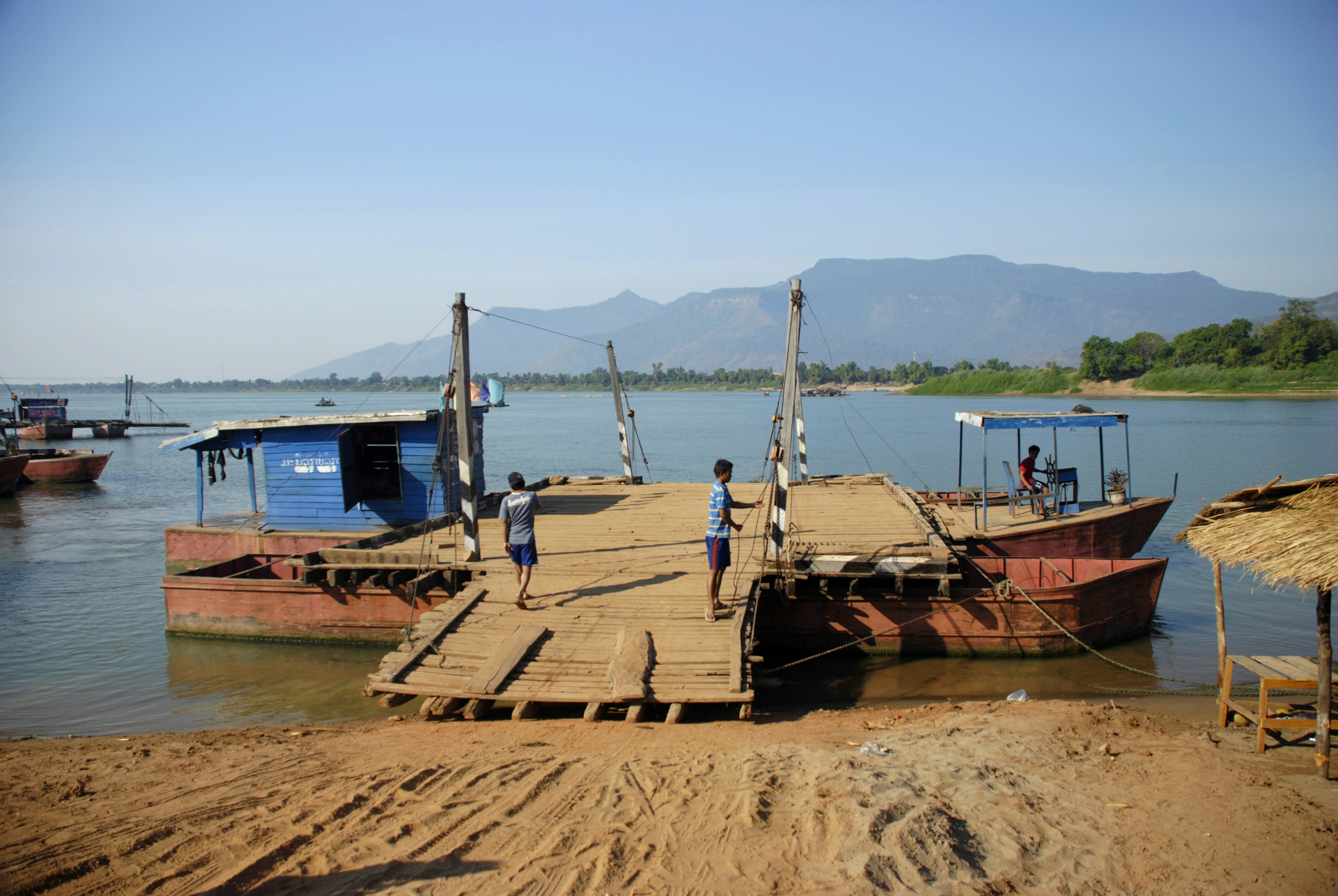 a group of boats sit on the shore of a lake, 