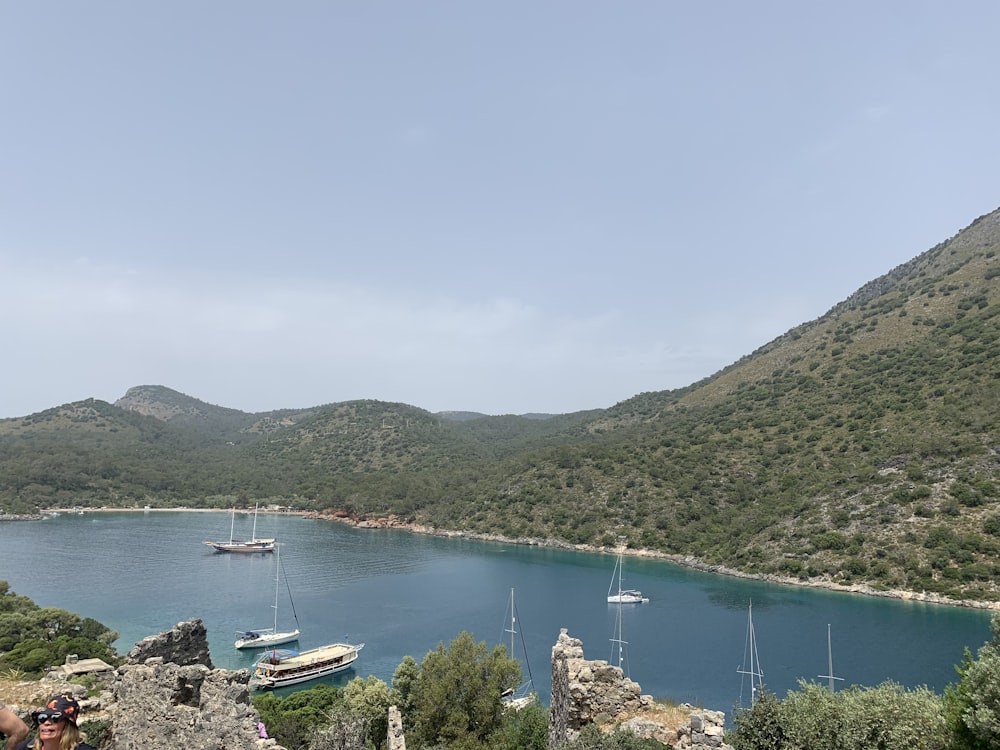 a body of water with boats in it and hills in the back