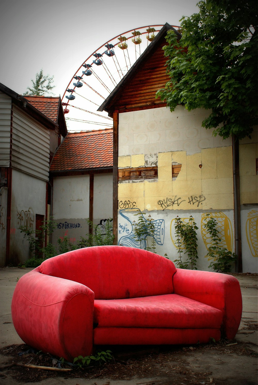 a red couch in front of a wall with graffiti