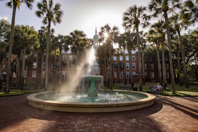 a fountain in a courtyard with trees and buildings in the background