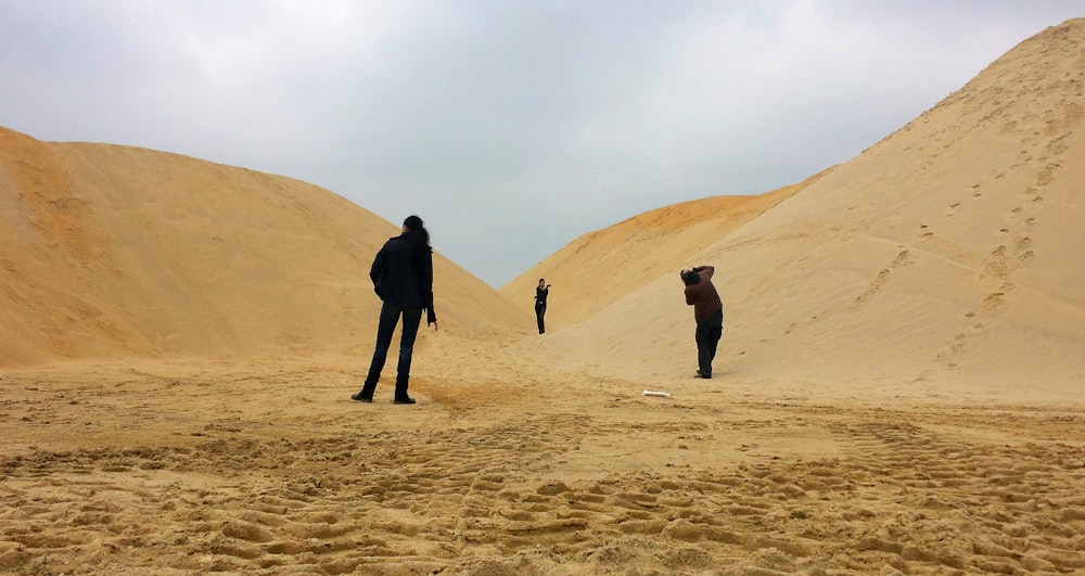 a group of people standing on a sandy hill
