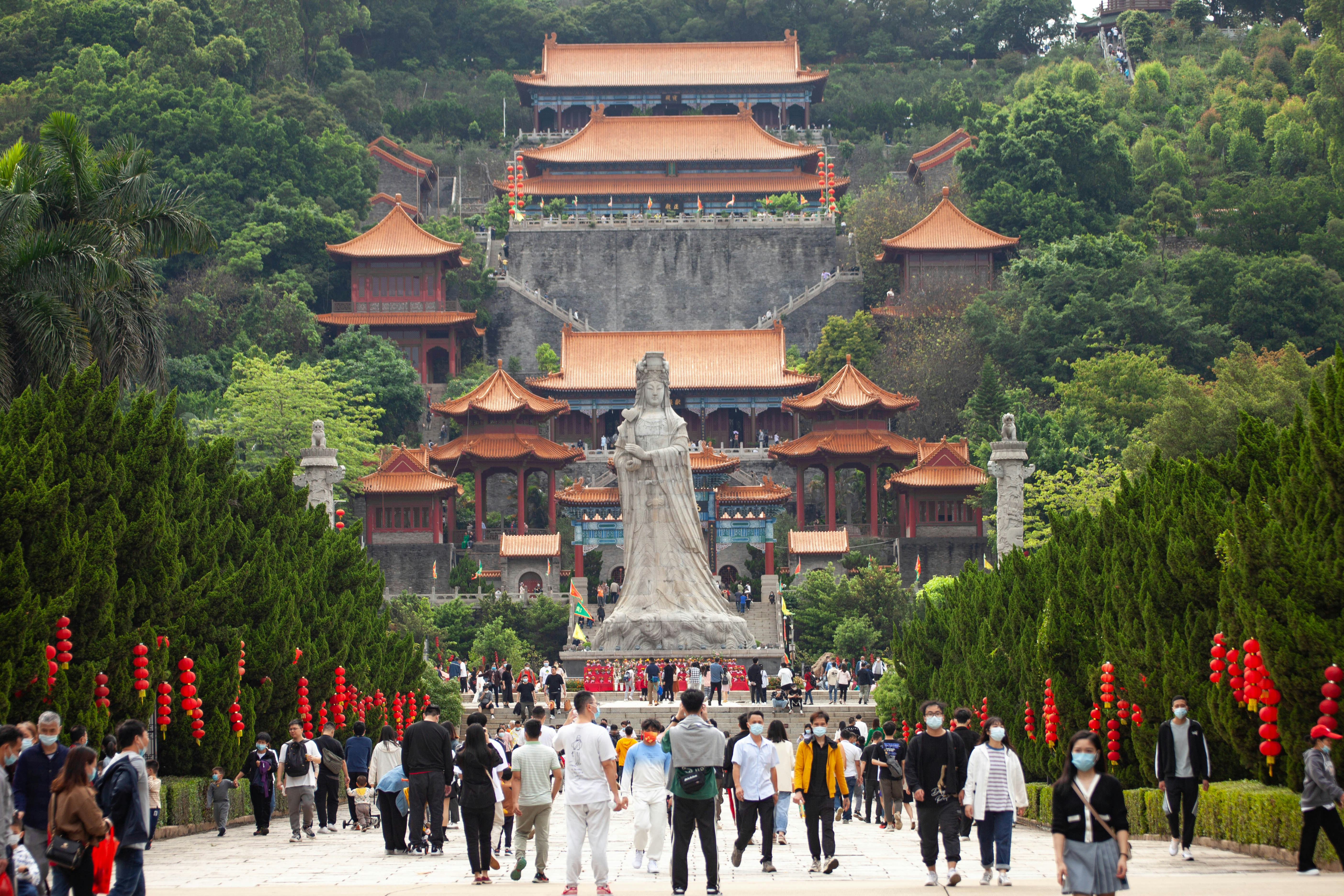a large group of people walking around a statue in front of a building