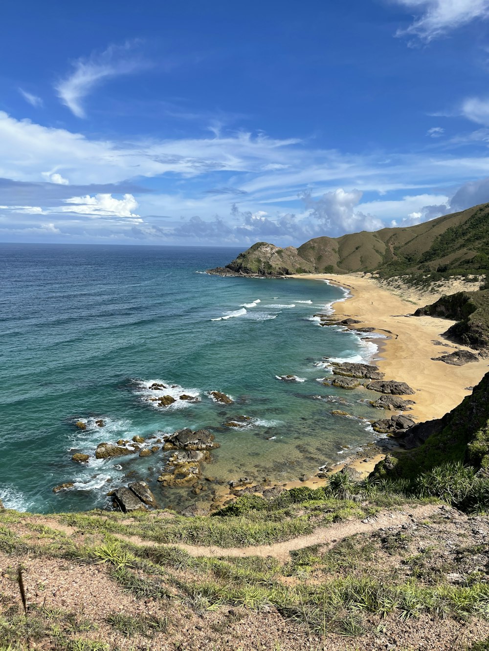 a rocky beach with a body of water and a blue sky