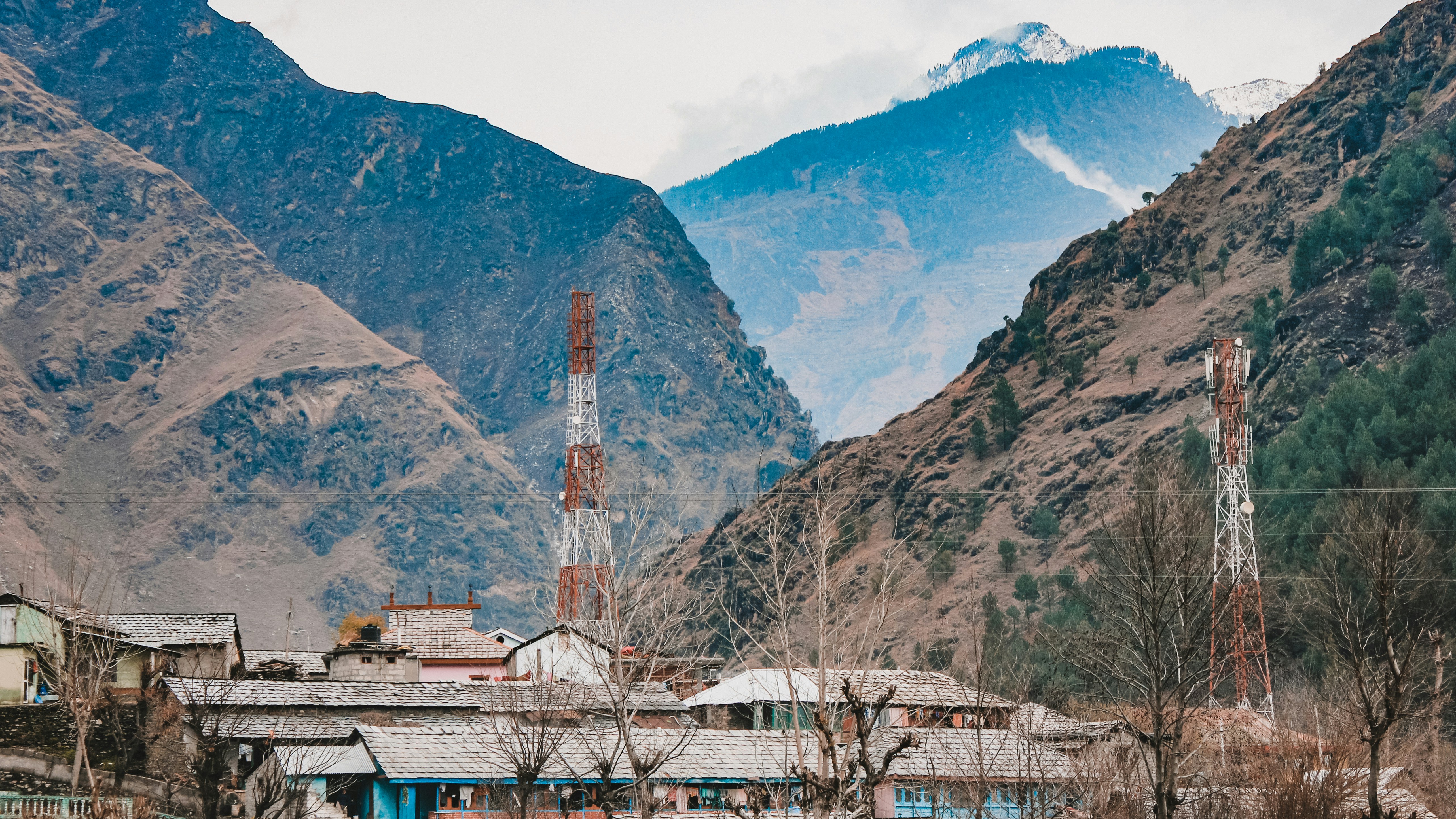 a building with a tower in the middle of a valley between mountains