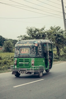 An e-rickshaw on the road, highlighting its robust battery pack beneath the seat.