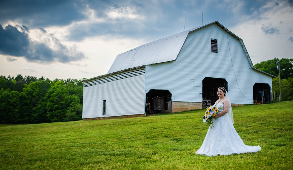 a person in a wedding dress in front of a barn