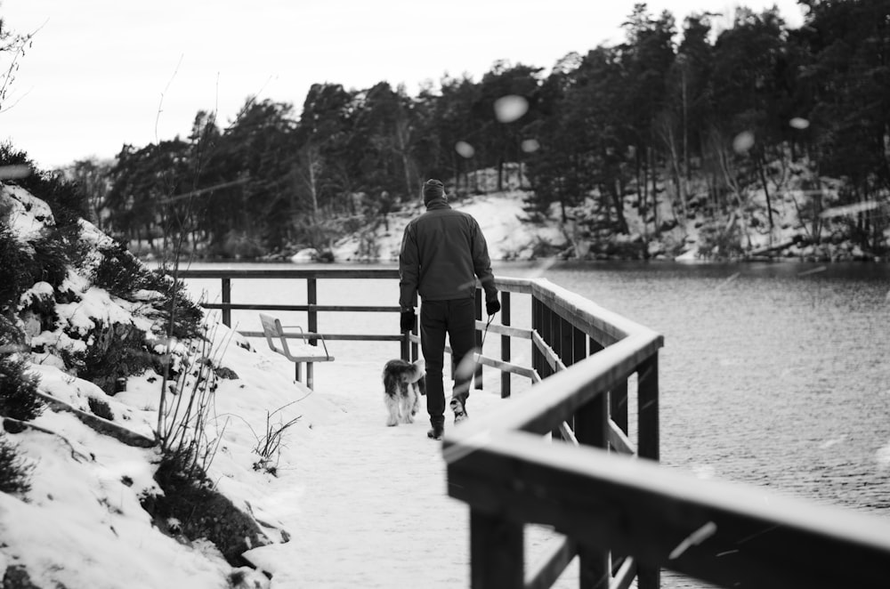 a man walking a dog on a bridge