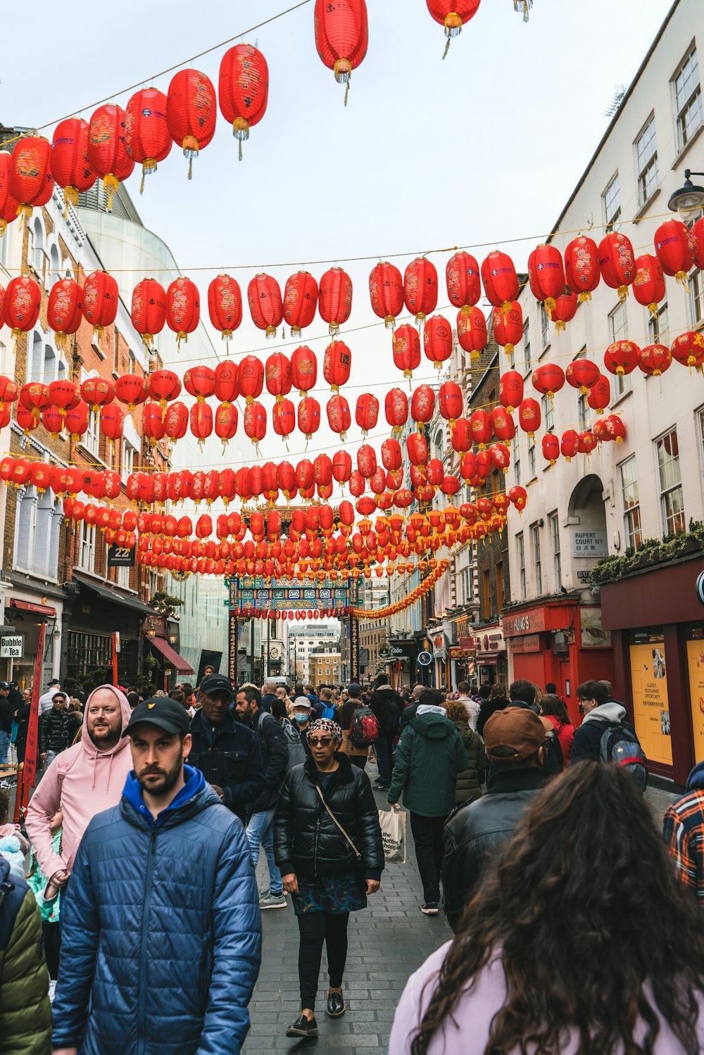 a group of people walking on a street with lanterns from the ceiling