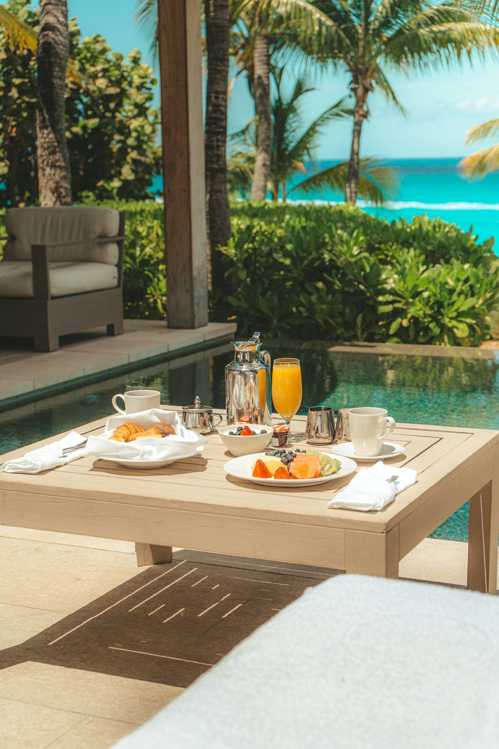 a table with food and drinks on it by a pool