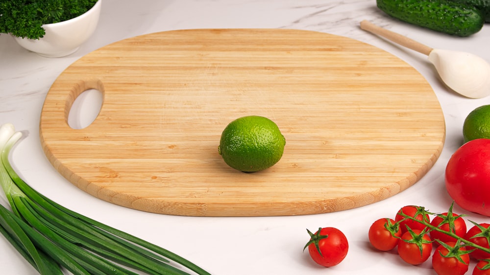 a cutting board with vegetables and a lime on it
