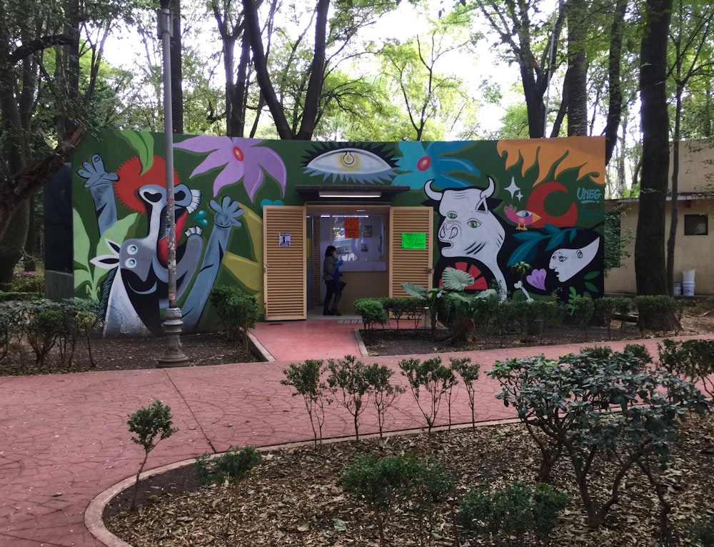 a person standing in front of a building with a mural on it