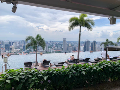 a group of people sitting at a table in front of a body of water with a city in