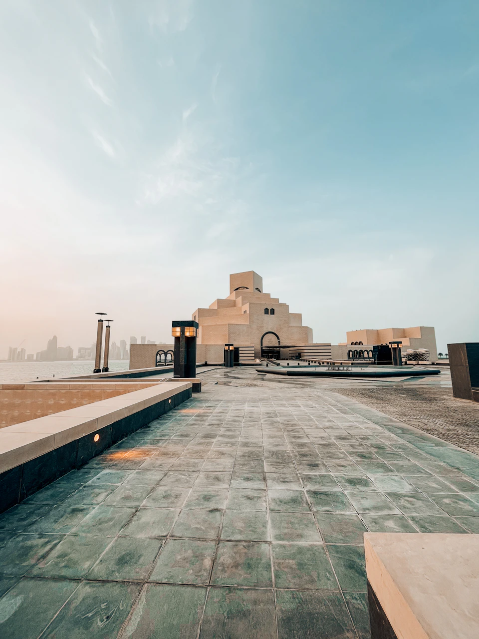 Large modern building with pyramid-like structure on beachfront location surrounded by walkway and benches