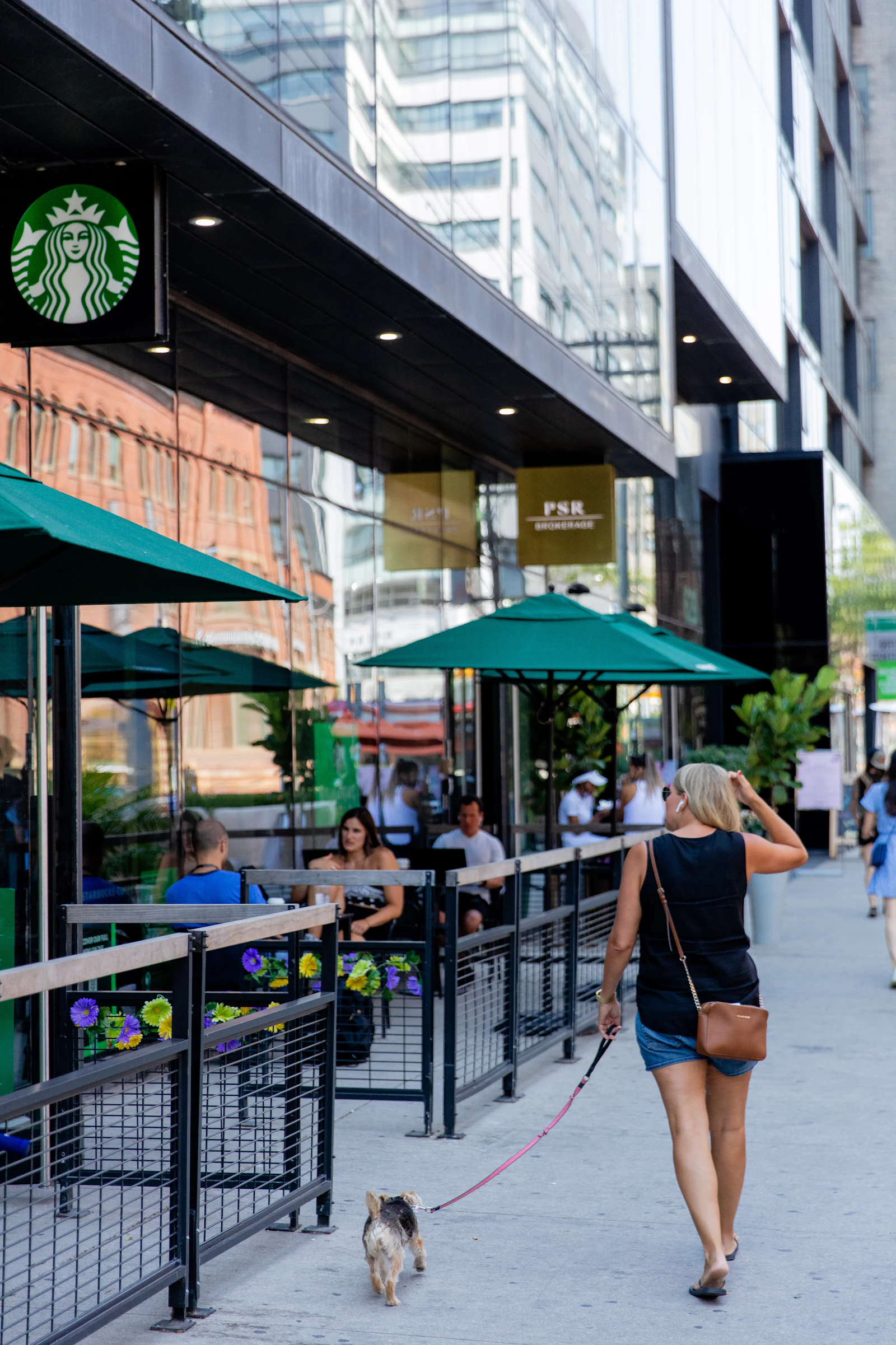 A person walking a dog on a city sidewalk