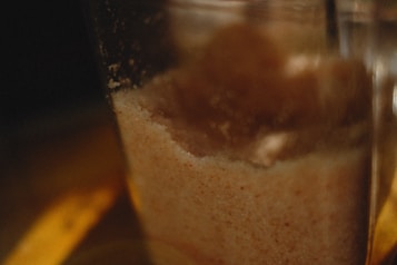 A close-up view of a container filled with granular material, possibly sugar or salt, with a blurry, warm-toned background.