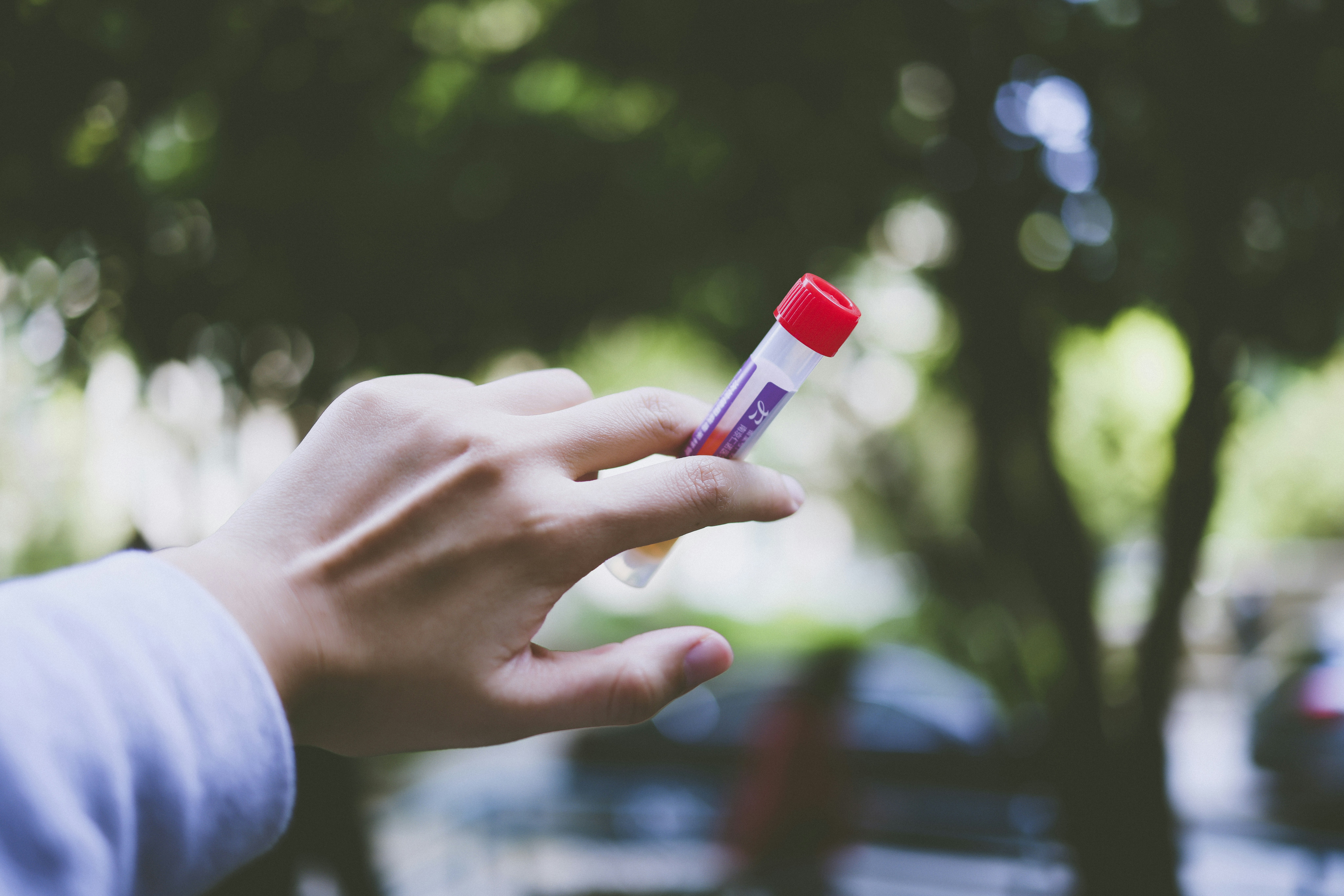 a person holding a small red and white tube