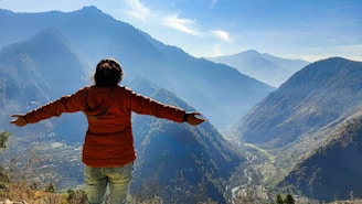 A person standing on a mountaintop at sunrise, arms wide open embracing the vast sky symbolizing freedom and new beginnings.