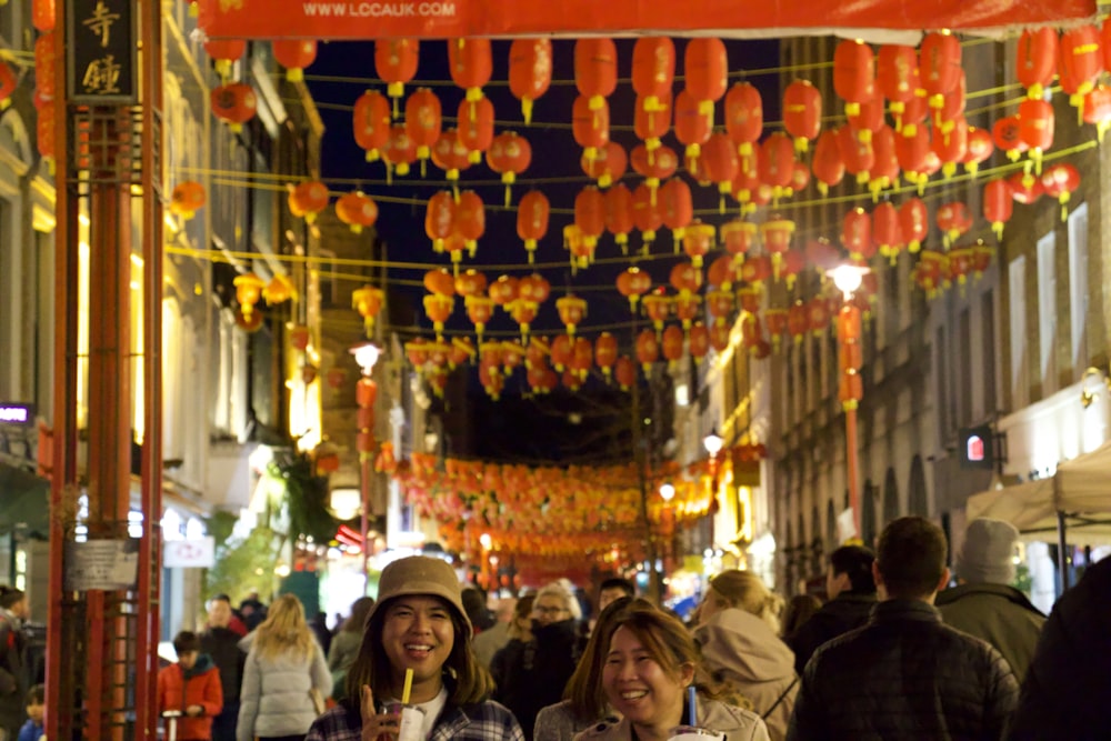 a group of people walking through a street with lanterns from the ceiling