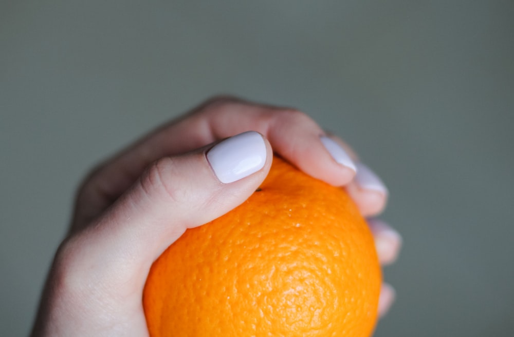 a hand holding an orange