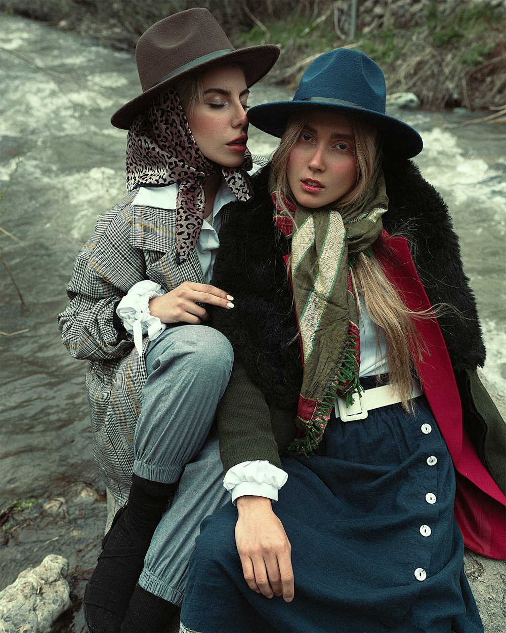 a couple of women wearing hats and sitting on a rock