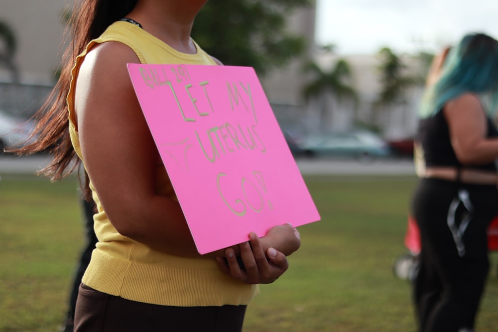 a woman holding a pink paper sign