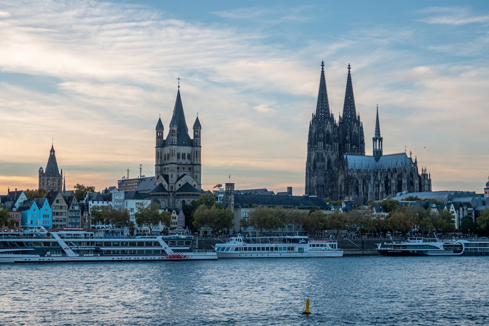 a body of water with a boat and buildings in the background with Cologne Cathedral in the background