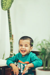 A friendly therapist engaging with a child in a bright, green-themed therapy room.