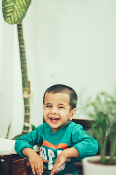 A friendly therapist engaging with a child in a bright, green-themed therapy room.