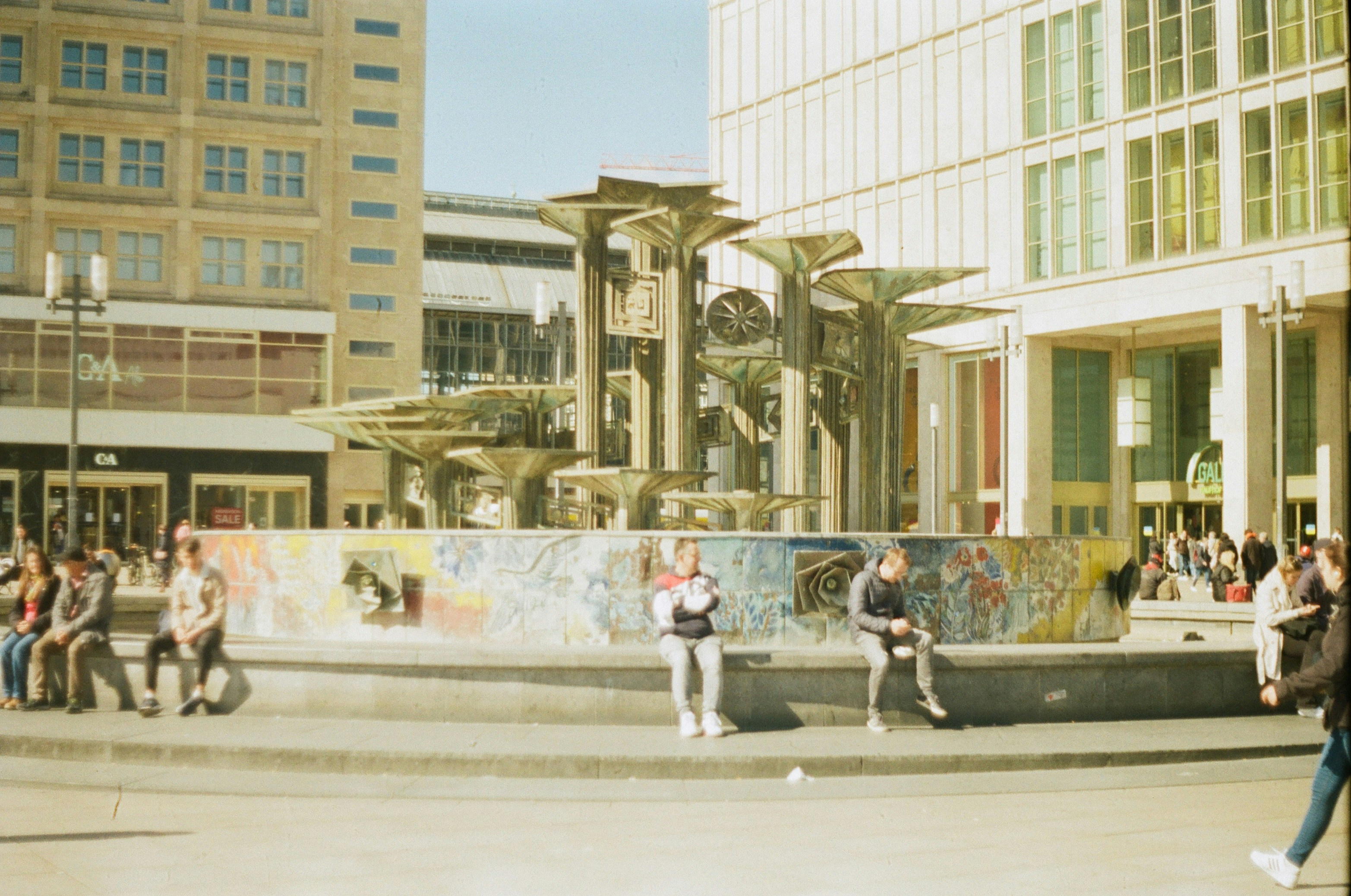 a group of people sitting on a bench in front of a fountain