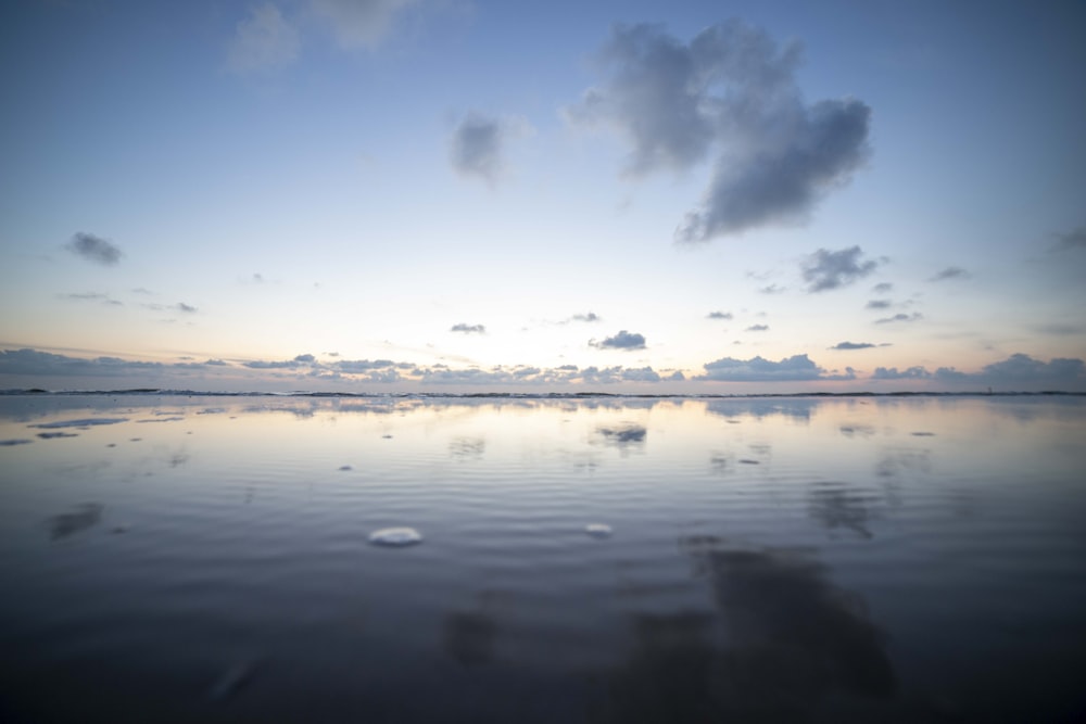 a body of water with clouds above it