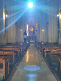 A luminous 3D point-cloud render of a historic church interior with glowing Gaussian splats highlighting stained glass and wooden beams
