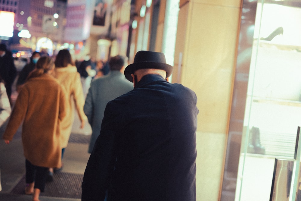 a man in a hat walking down a sidewalk
