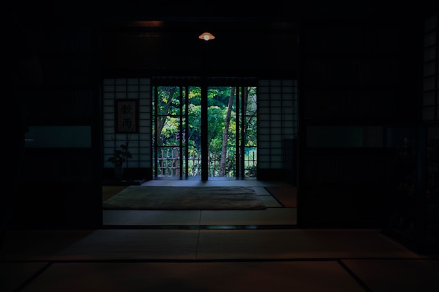 A cozy Japanese ryokan reception warmly greeting Indonesian guests with traditional decor in the background.