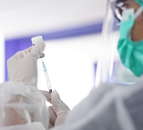 a person in a mask and gloves holding a syringe