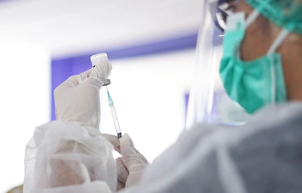 A nurse preparing a vaccine in a clean, welcoming clinic setting.