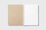 A simple notebook with a plain cover lying open on a desk.