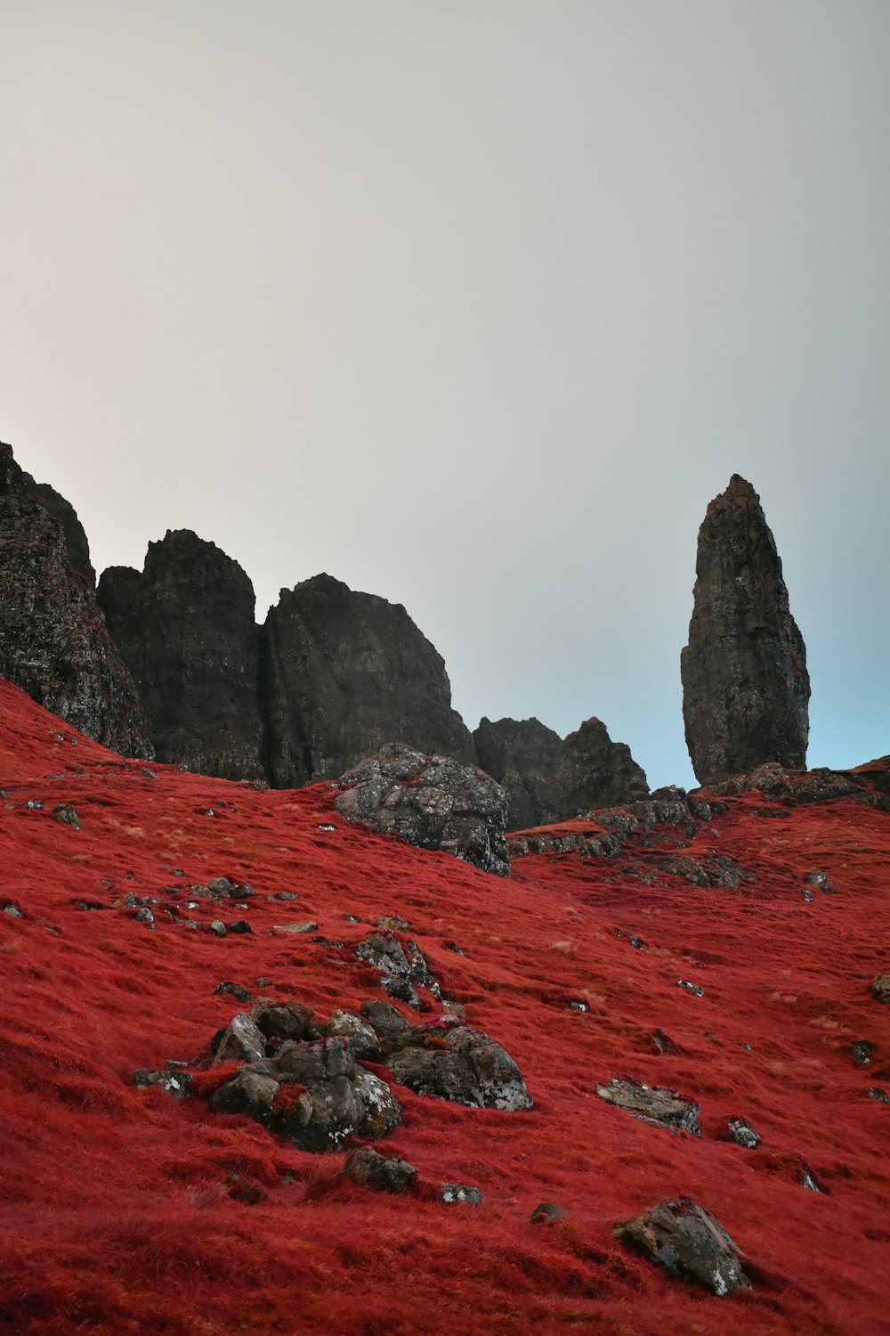 a rocky mountain with a red dirt ground