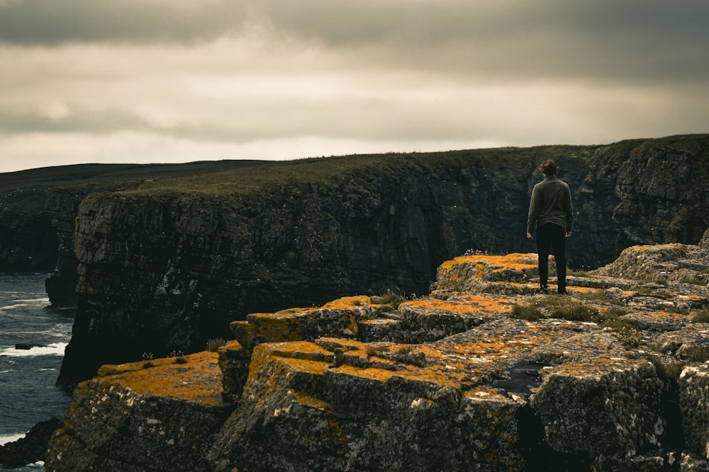 Un uomo in piedi su una scogliera rocciosa