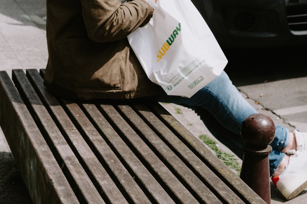 a person sitting on a bench with a bag of food