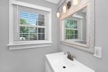 A bright bathroom featuring modern fixtures and a large mirror reflecting soft natural light.