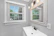 Bright bathroom featuring a large Belgian mirror reflecting natural light.