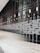 A modern interior space with a large reflective wall and an array of lights hanging from the ceiling. The wall features a series of horizontal patterns, and the reflection creates a distorted visual effect. The floor is polished and shiny, adding to the sleek design.