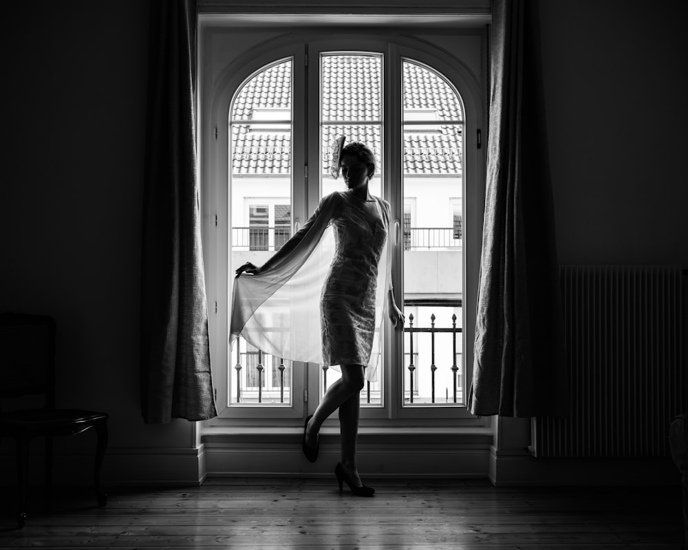 a man in a dress dancing in a room with a window
