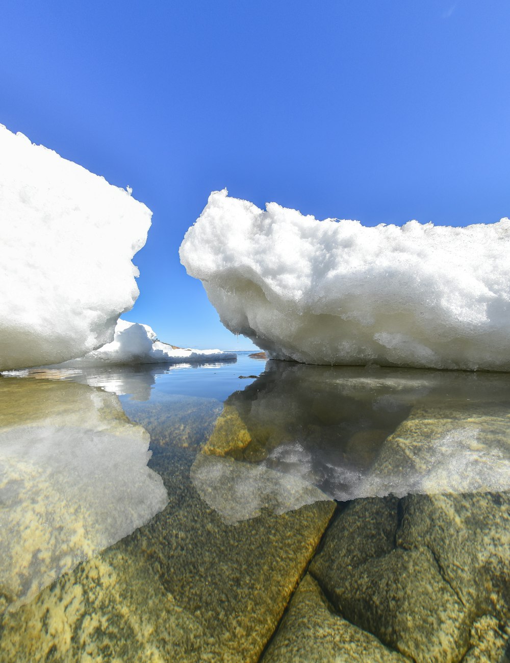 a body of water with ice and snow on the sides